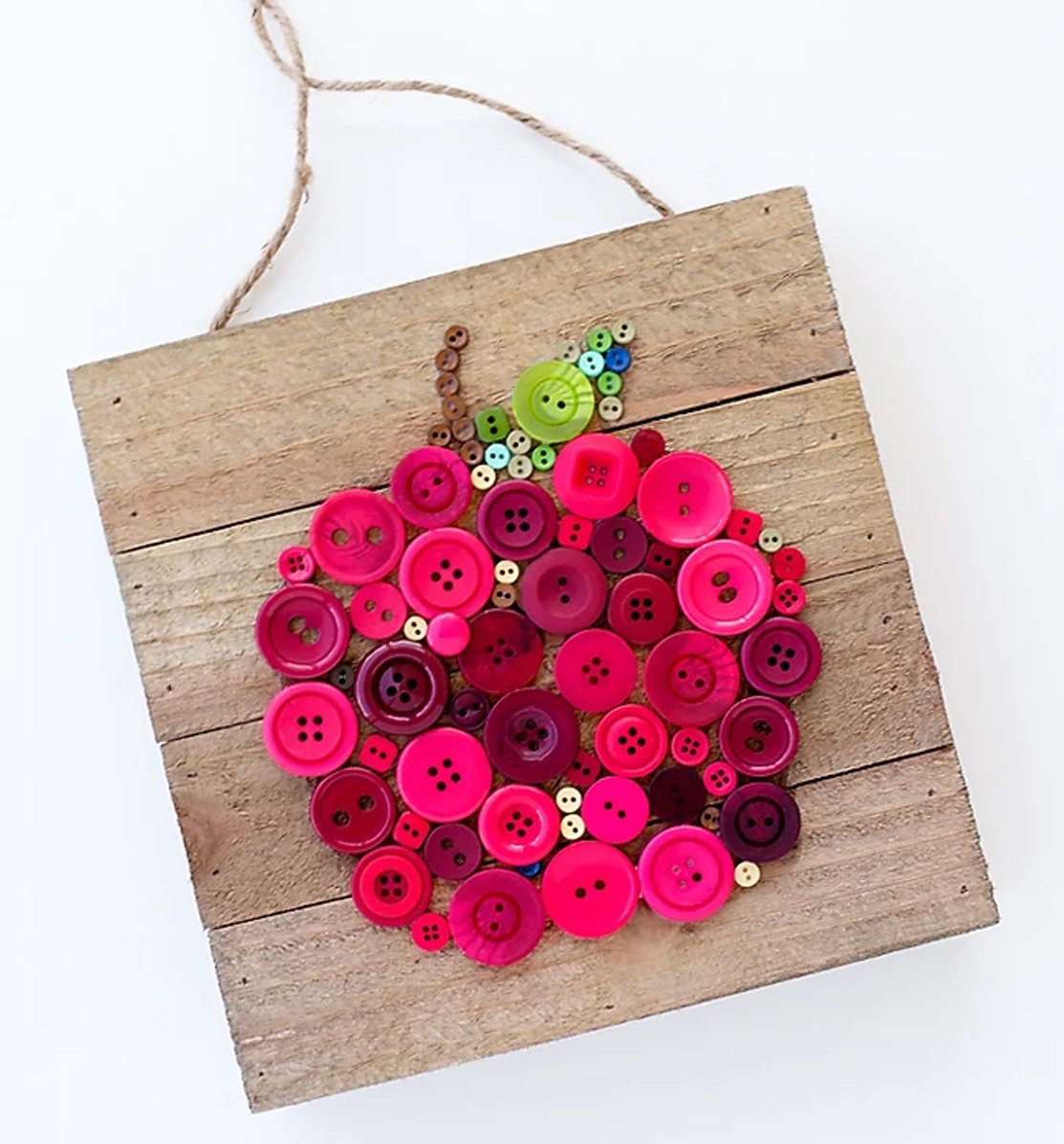 An apple craft made out of red buttons glued onto a wooden board.