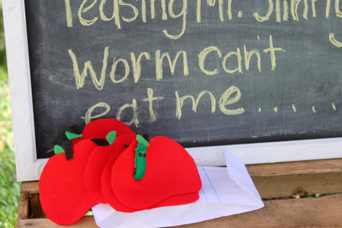A compilation of apple crafts made with felt, in front of a chalkboard