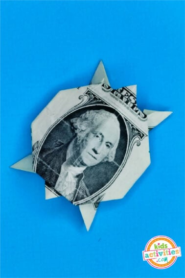 Final Result of a dollar bill Origami Turtle on top of a blue background