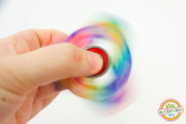 How to Make Fidget Spinners - final image of fidget spinner craft in action spinning with rainbow colors - Kids Activities Blog