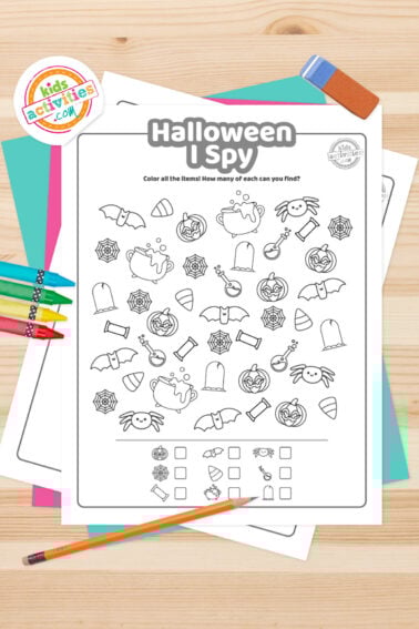 Black and white I spy Halloween printable lying on top of a blue-green sheet with multicolored letters on a light brown background. printed pdf version from Kids activities blog.