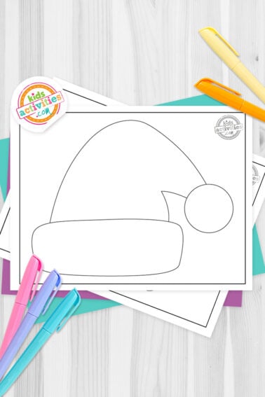 Black and white Santa hat template printables on top of blue-green and purple sheets with assorted markers on a dark grey background. printed pdf version from Kids activities blog.