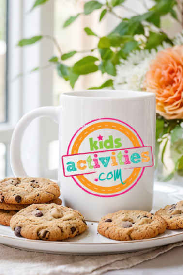 kids activities blog logo on a white ceramic coffee mug surrounded by chocolate chip cookies