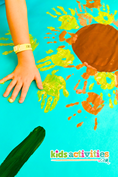 Sunflower Handprint Art Painting for kids. Image of kid making yellow handprint on sunflower painting. - kidsactivityblog.com